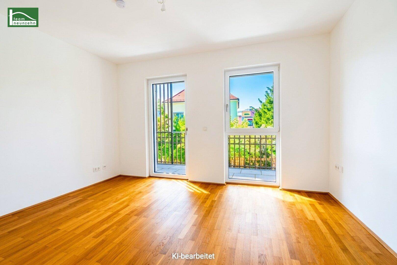 Geräumiges Zimmer mit Holzboden und zwei Fenstertüren zu französischen Balkonen.