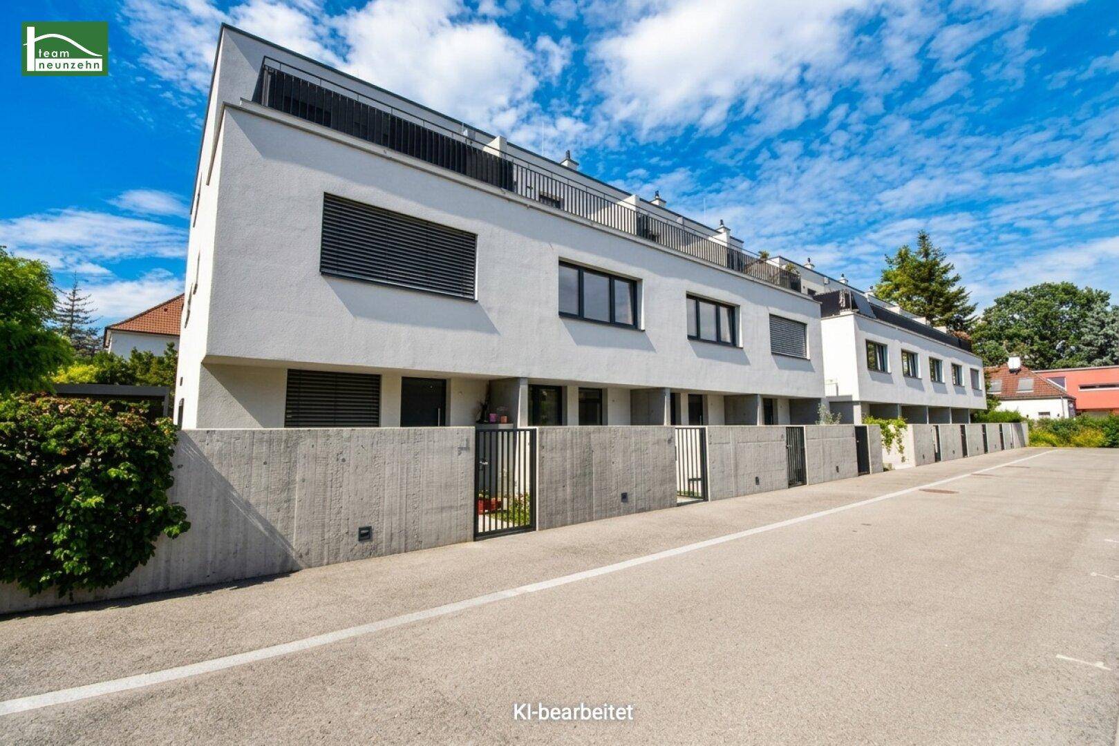 Moderne Reihenhäuser mit weißer Fassade, Balkonen und Betonmauern entlang der Zufahrt.