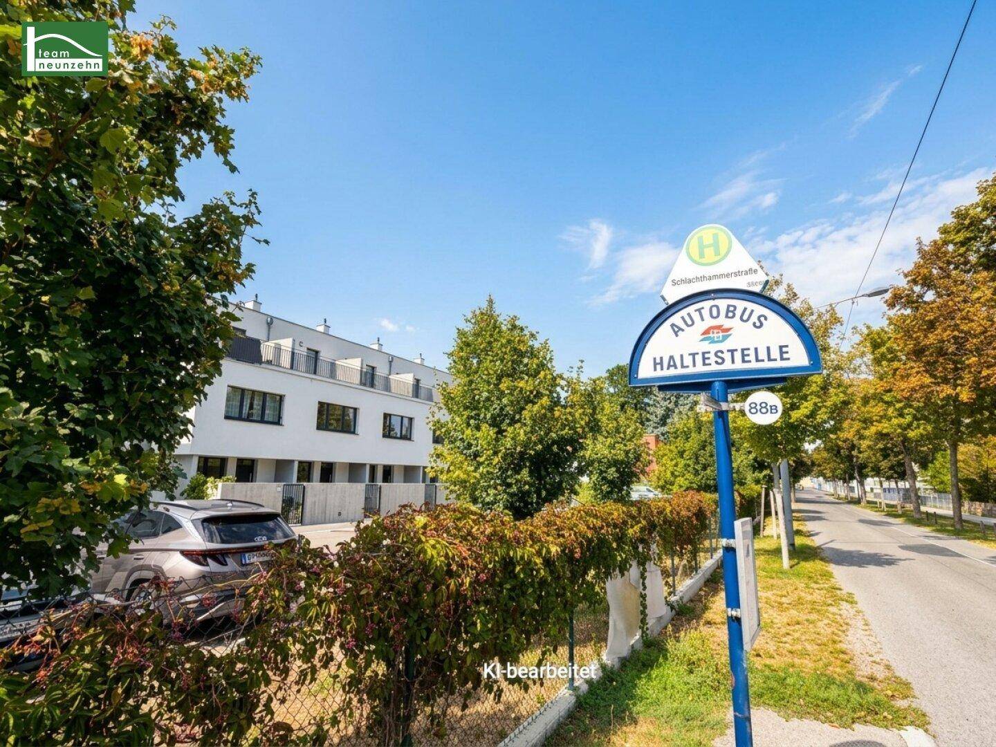 Bushaltestelle an einer Straße mit modernen Wohngebäuden und viel Grün im Hintergrund.