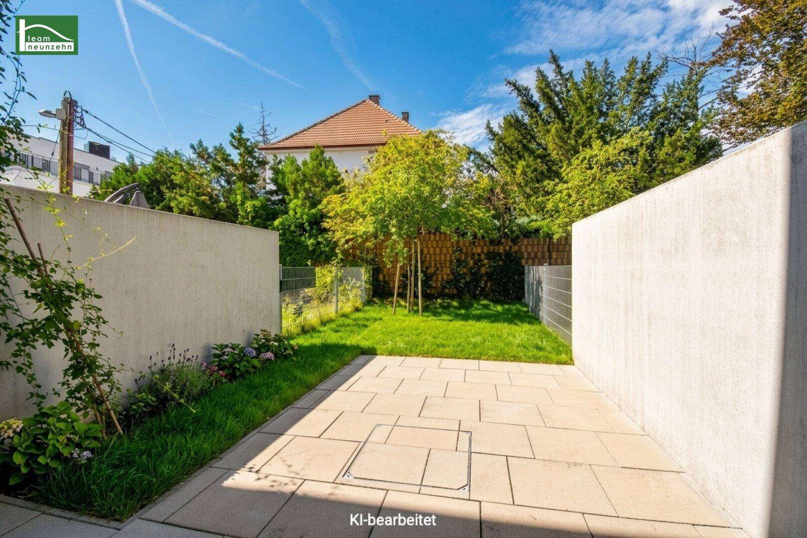 Sonniger Terrassenbereich mit Steinplatten und kleinem Rasenstück, umgeben von Grün.
