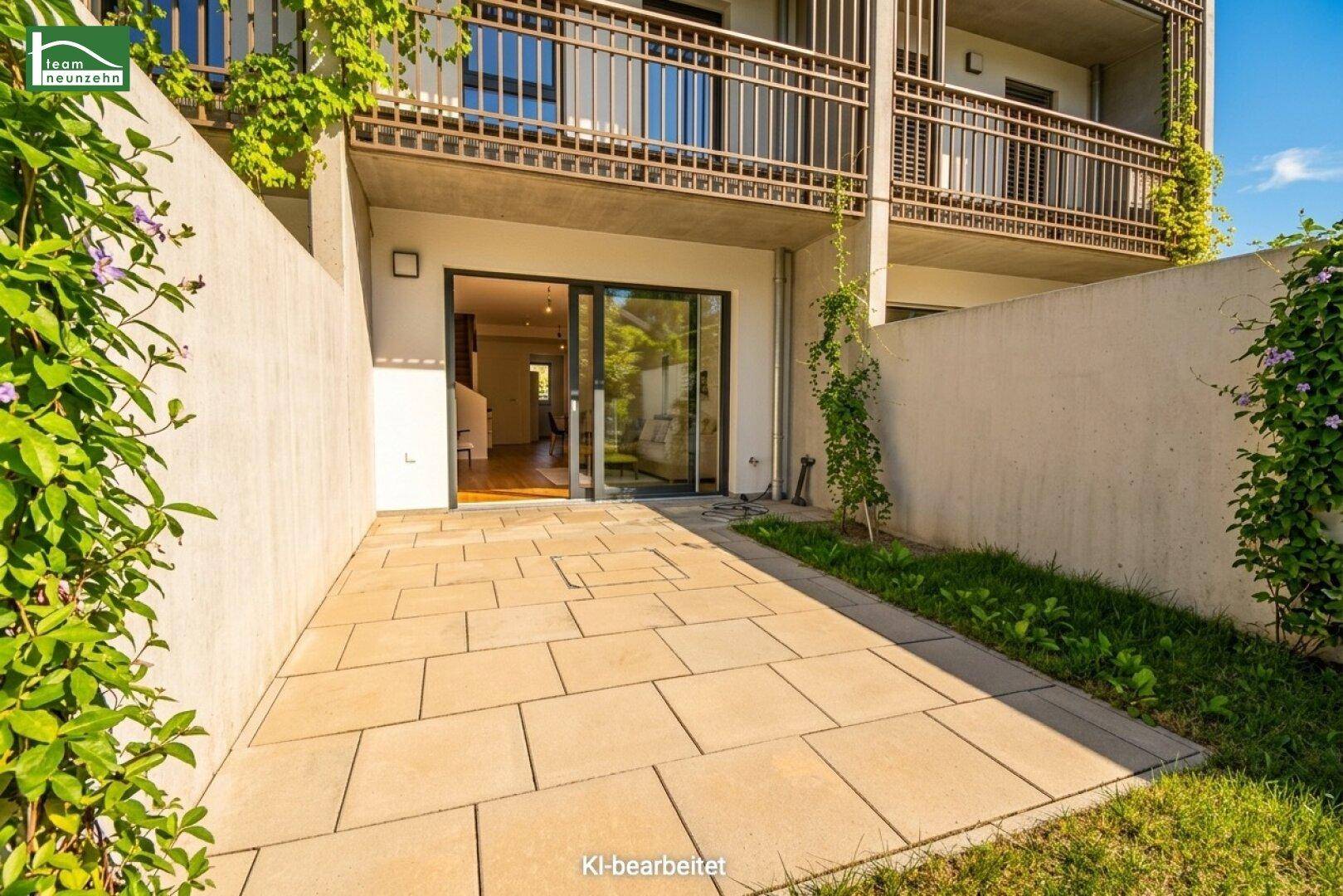 Gepflasterte Terrasse im Erdgeschoss, umgeben von Mauern und Pflanzen.