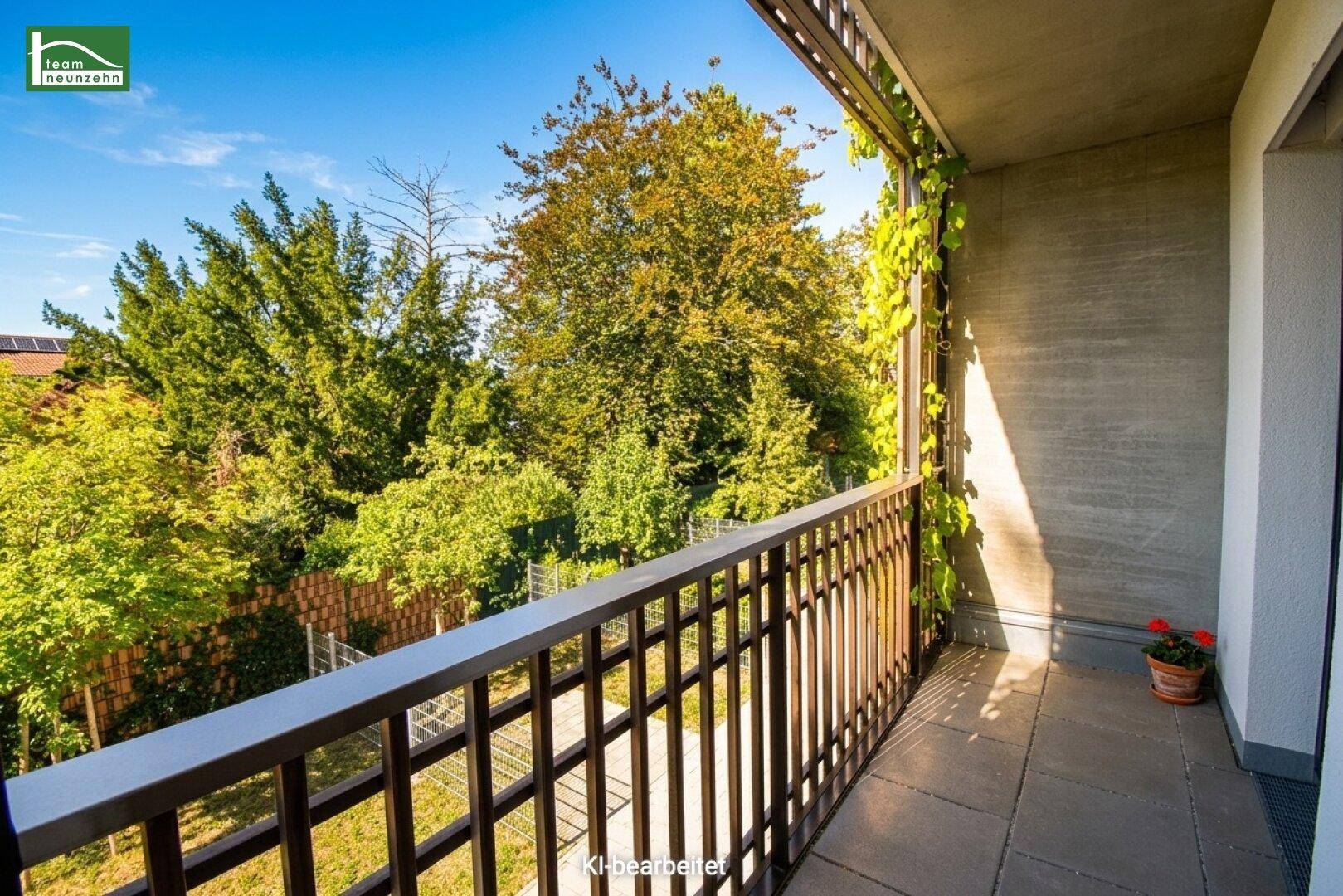 Sonniger Balkon mit Metallgeländer und Blick auf üppiges Grün.