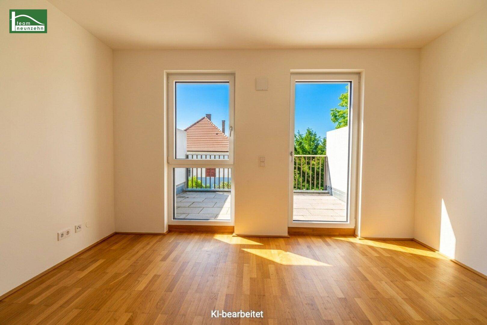 Helles Zimmer mit Parkettboden und Zugang zu einem Außenbereich mit Blick auf Dächer.