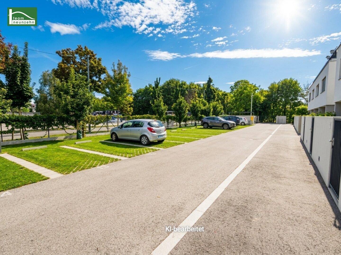 Außenparkplätze mit Rasengittersteinen und Bäumen im Hintergrund unter blauem Himmel.