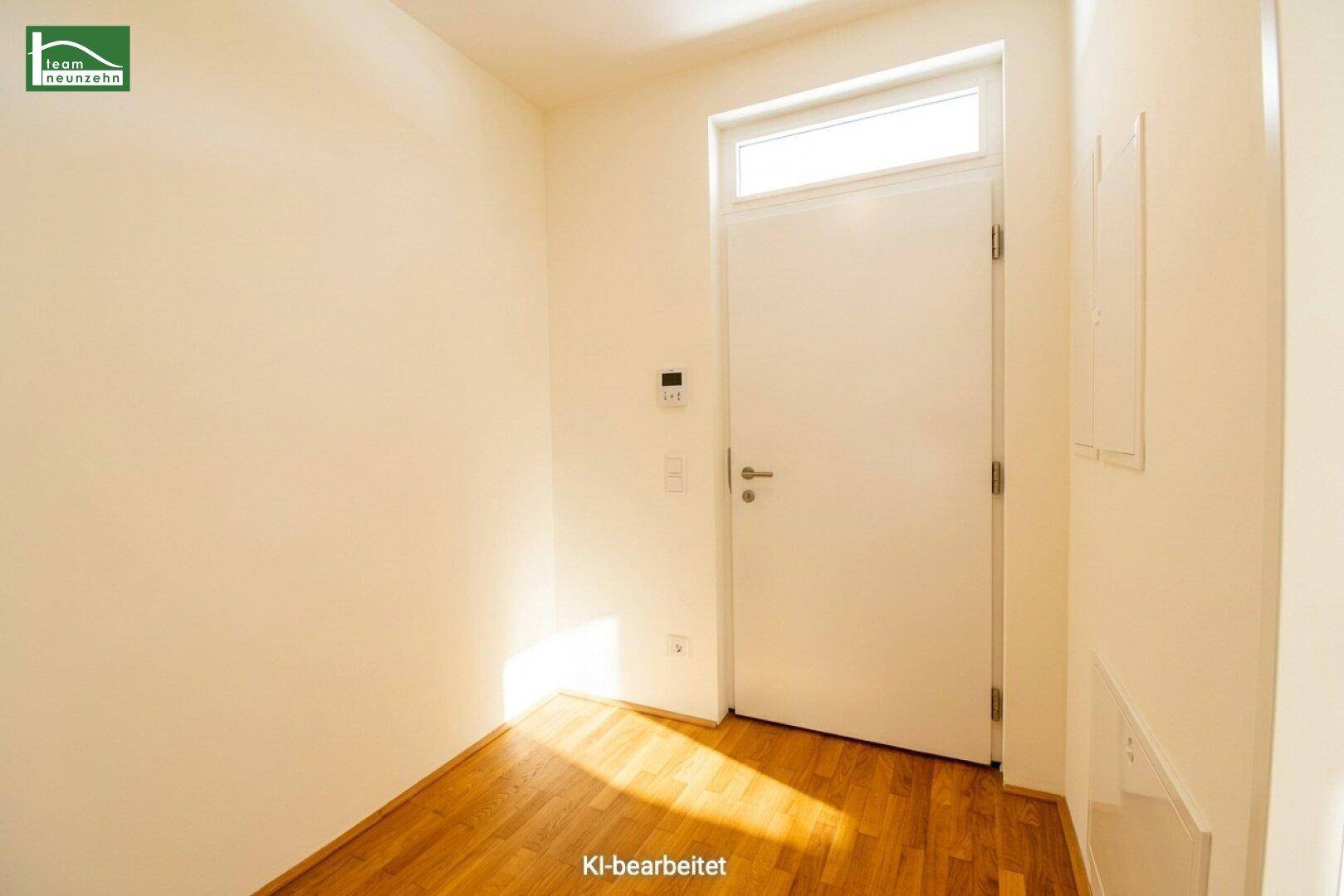 Eingangsbereich mit Holzboden und weißer Tür, bietet Platz für Garderobe und empfängt Tageslicht.