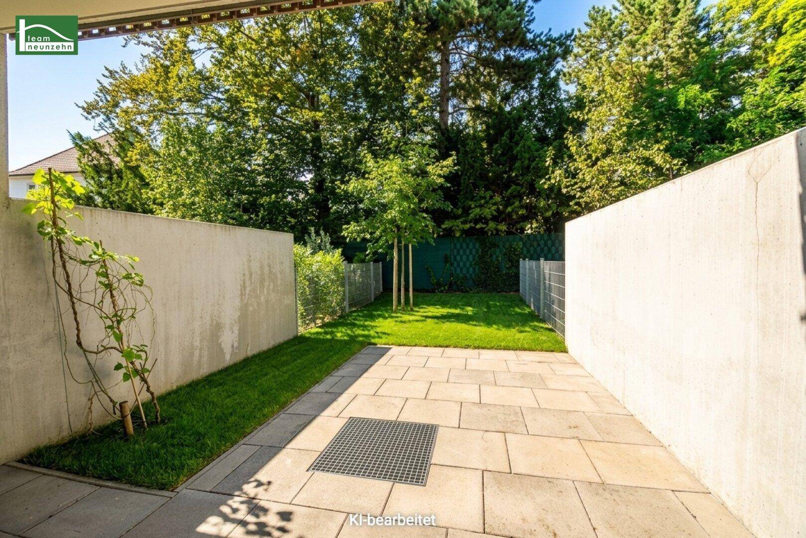 Kleiner, pflegeleichter Garten mit Rasenfläche und gepflasterter Terrasse, umgeben von hohen Mauern.
