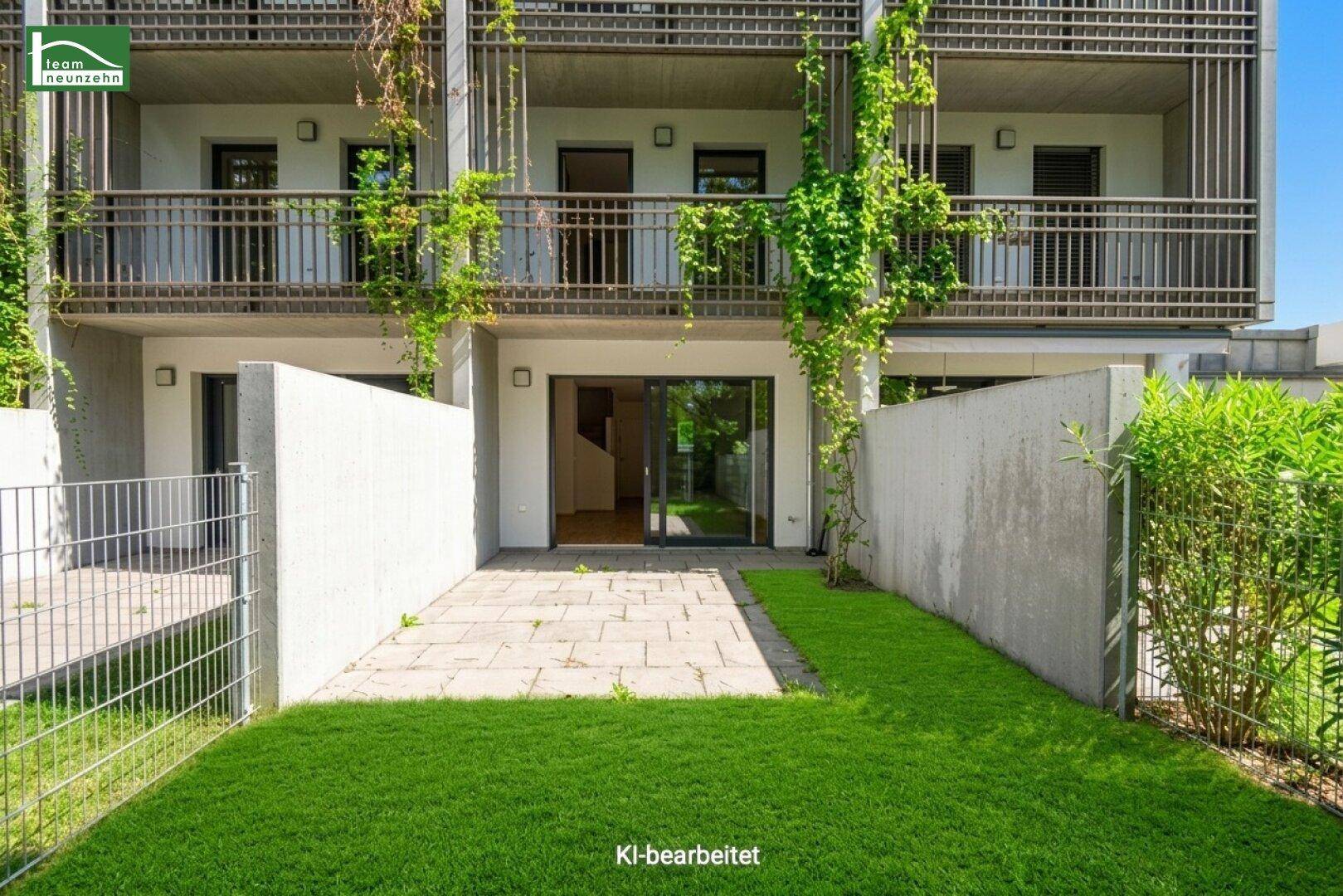 Hinterhof mit Rasenfläche und Terrasse, Blick auf die modernen Balkone des Gebäudes.