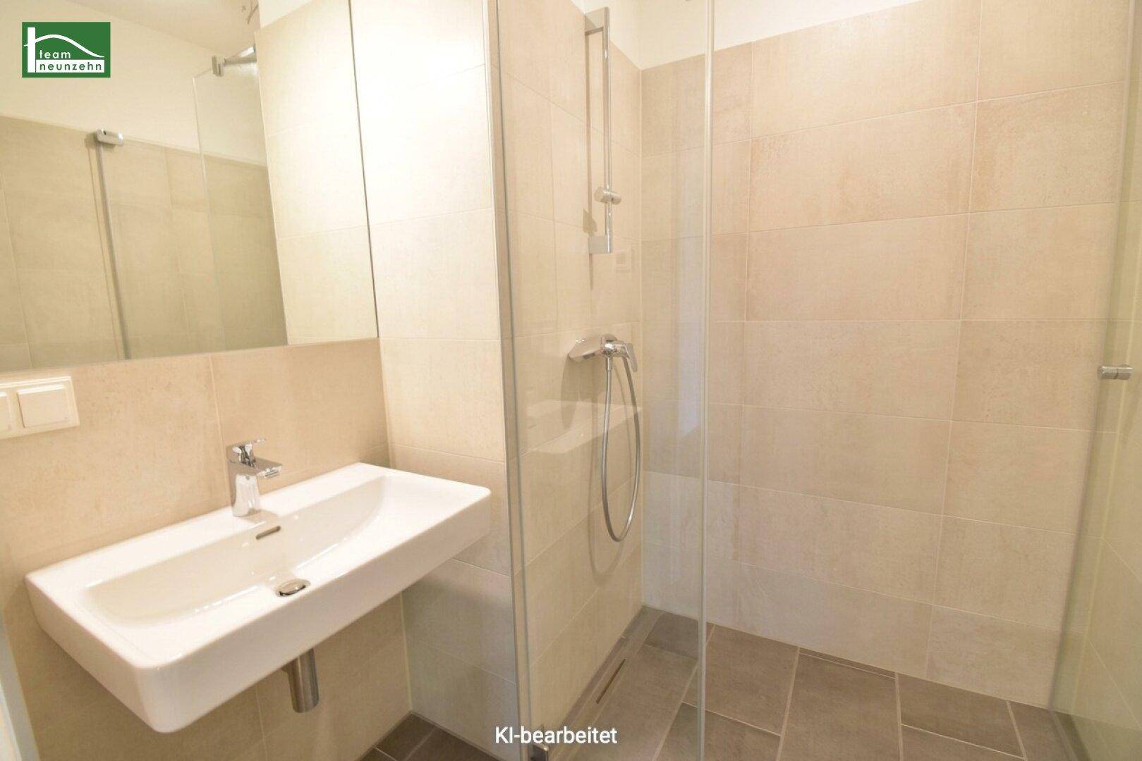Modernes Badezimmer mit ebenerdiger Dusche und Einzelwaschbecken, in hellen Beigetönen gefliest.