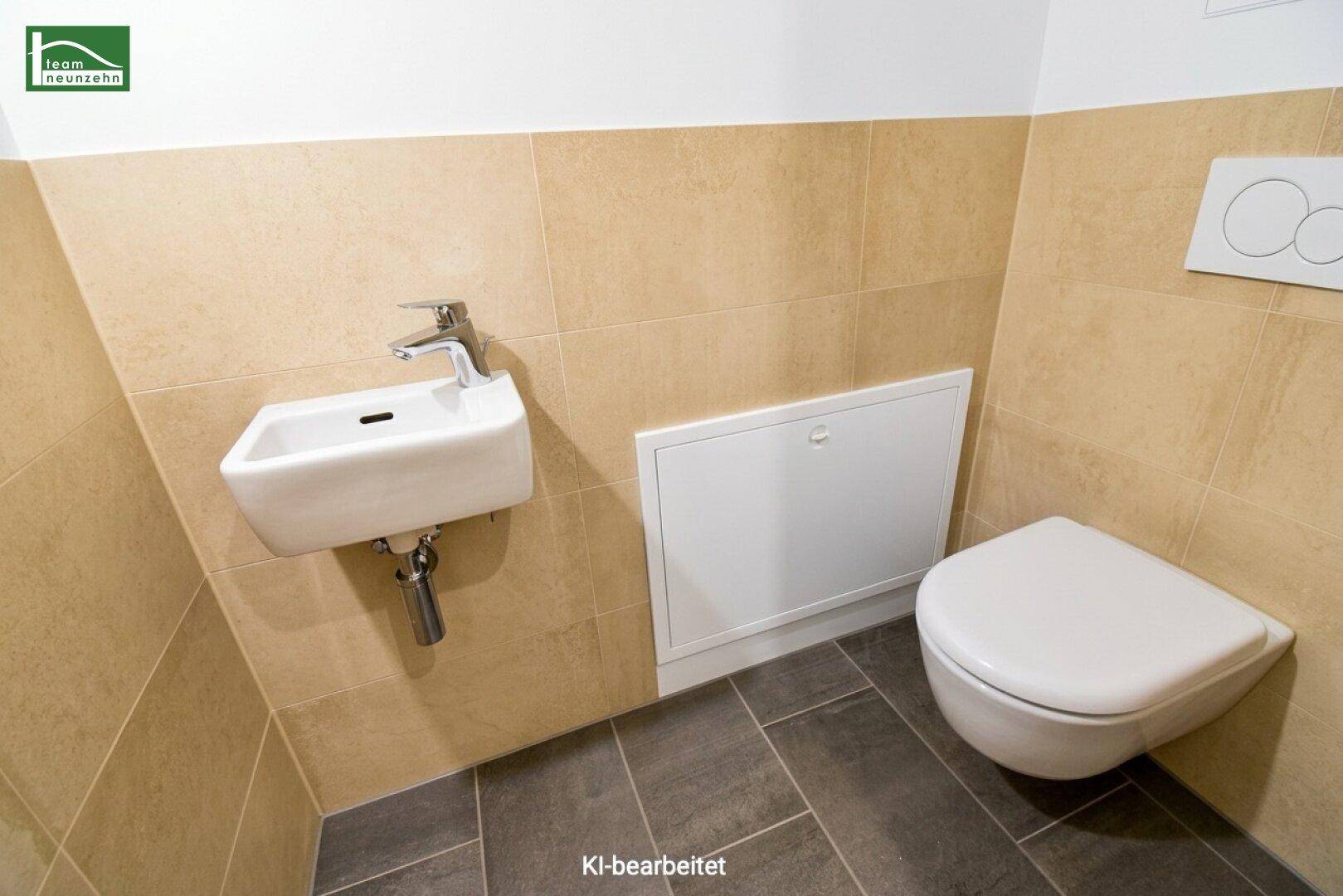 Funktionales Gäste-WC mit Wand-WC und kleinem Waschbecken, ausgestattet mit beigen und grauen Fliesen.