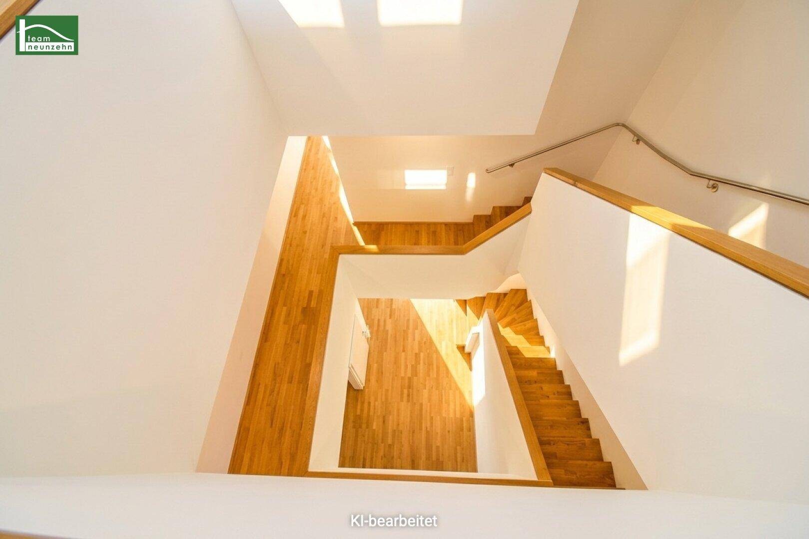 Beeindruckendes Treppenhaus mit Holzstufen und viel Tageslicht von oben, verbindet die Etagen elegant.