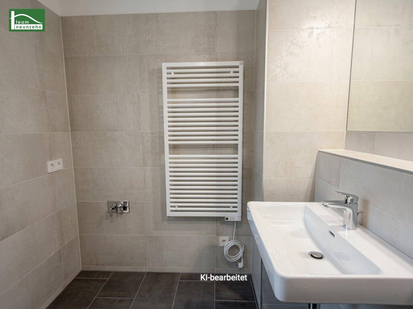 Badezimmer mit modernem Waschbecken und beheiztem Handtuchhalter, in neutralen Farben gefliest.
