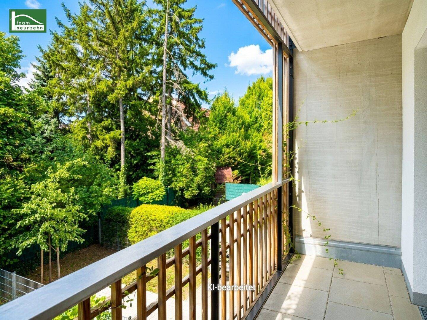 Sonniger Balkon mit Holzgeländer und weitem Blick auf die umliegenden grünen Bäume.
