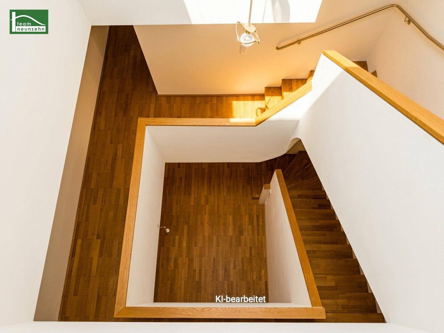 Blick von oben auf die moderne Holztreppe, die sich über mehrere Etagen erstreckt und viel Licht erhält.