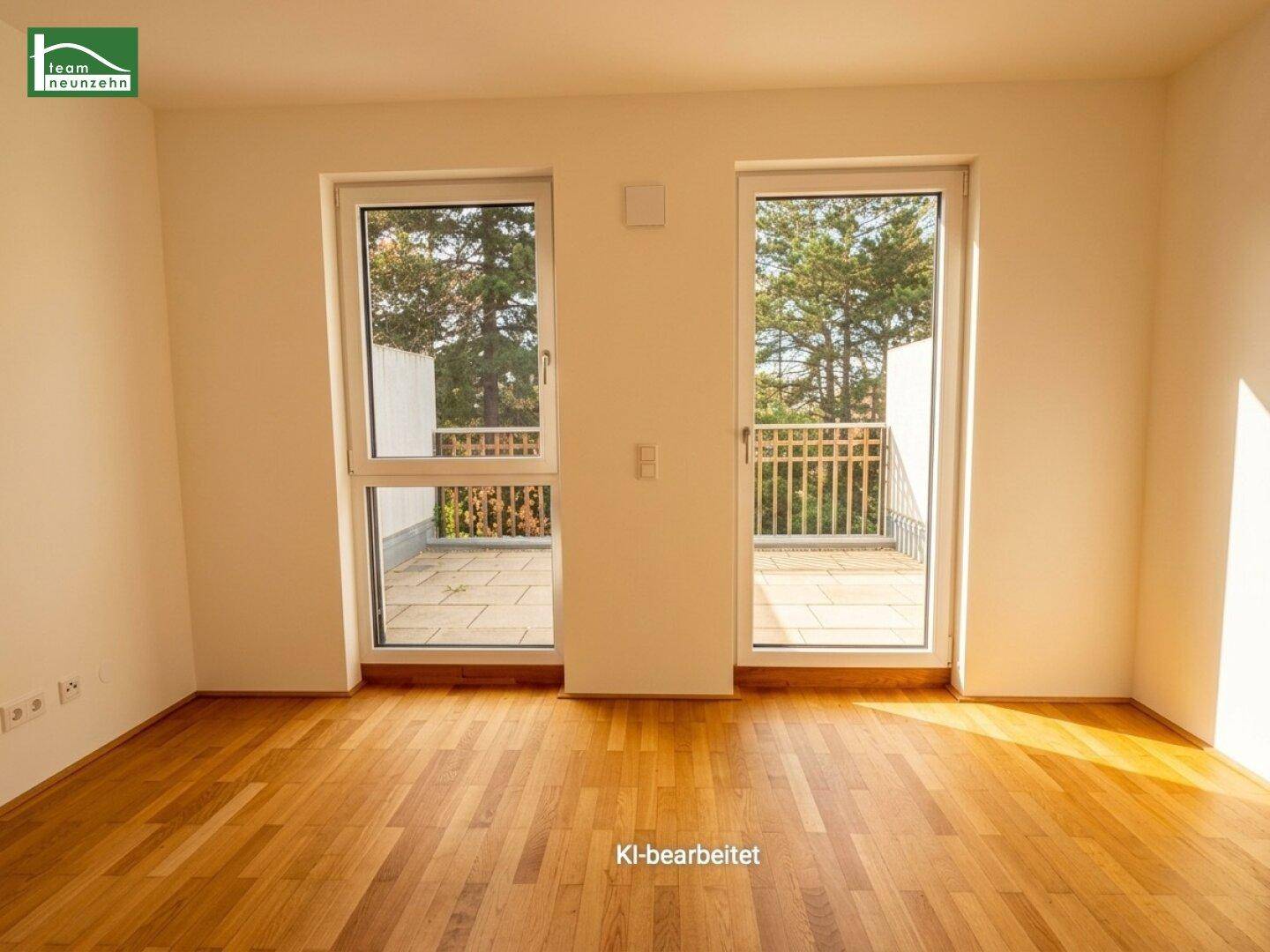 Heller Raum mit warmem Holzboden und zwei großen Fenstertüren, die auf eine Terrasse führen.