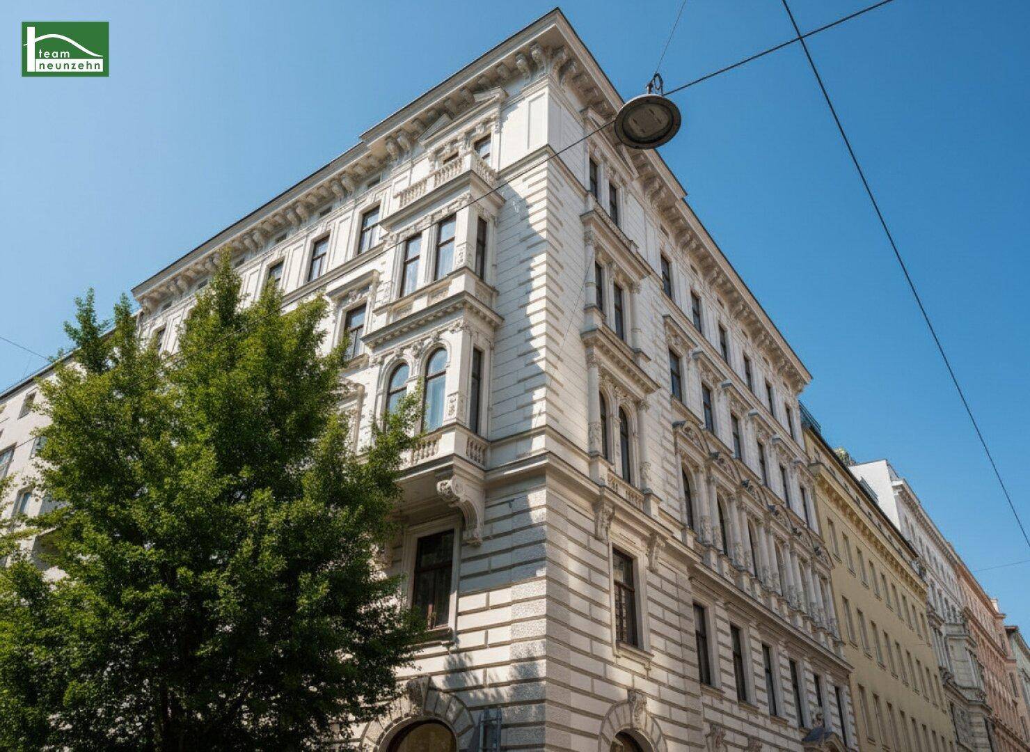 Historisches Eckgebäude mit reich verzierter Fassade und vielen Fenstern unter blauem Himmel.