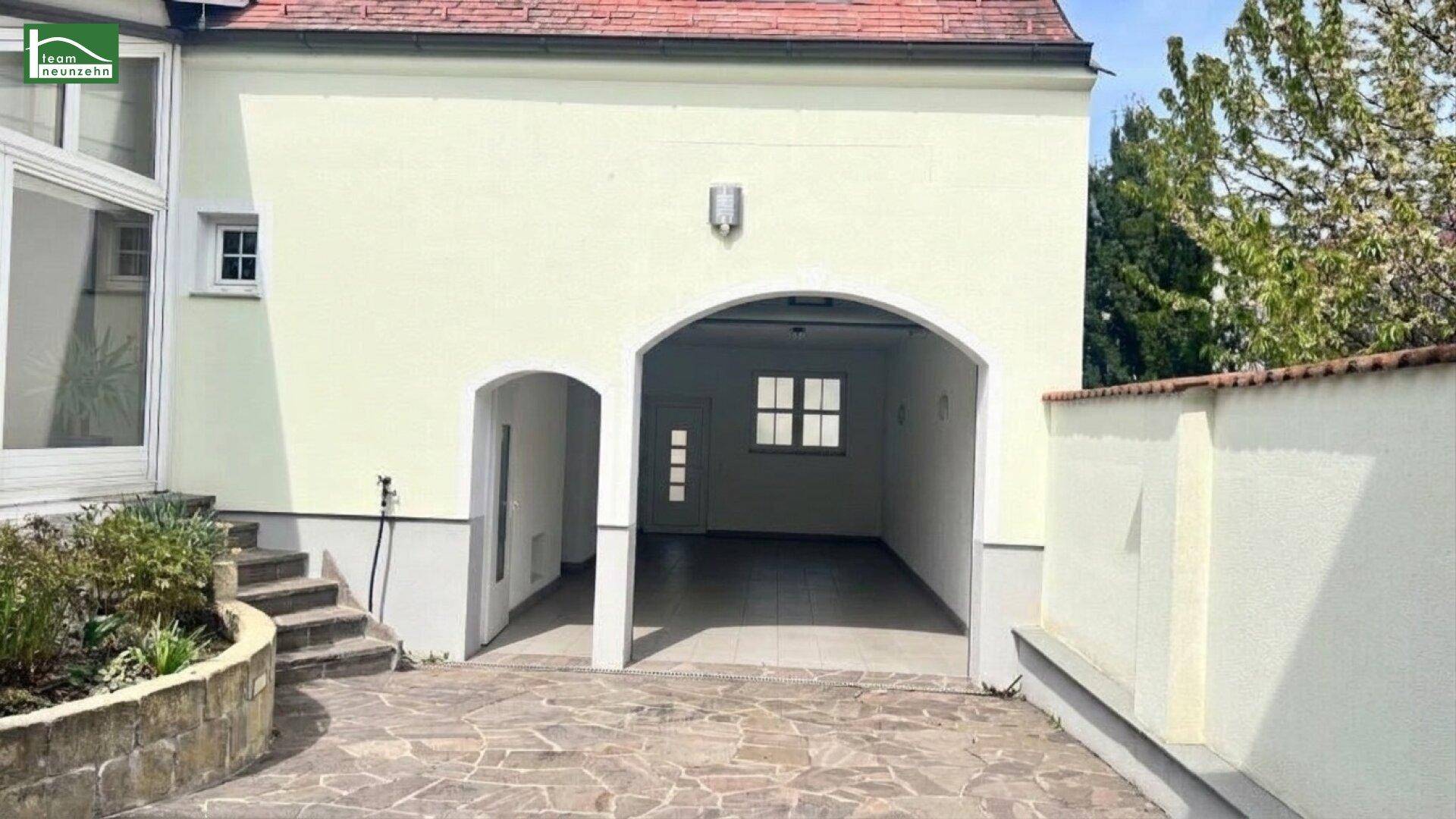 Überdachter Eingangsbereich oder Carport mit Bogenarchitektur und gepflastertem Boden.
