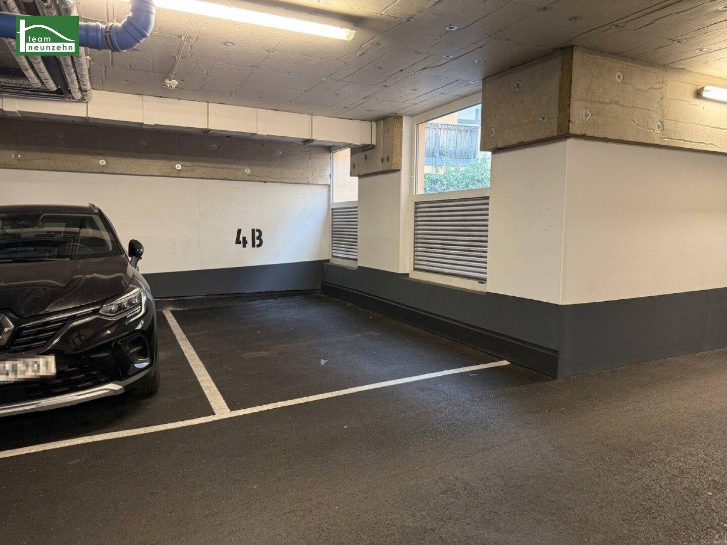 Tiefgaragenstellplatz 4B mit einem geparkten Fahrzeug und Fenstern zur Belüftung.