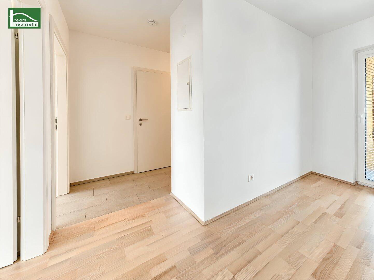 Heller Übergangsbereich mit Holzboden und Fliesen, der zu verschiedenen Räumen führt.