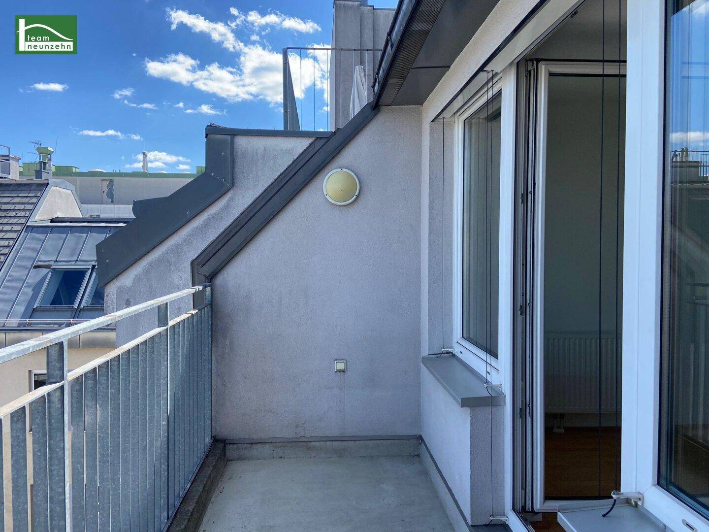 Kleiner Balkon mit Metallgeländer und Blick über die Dächer der Stadt.