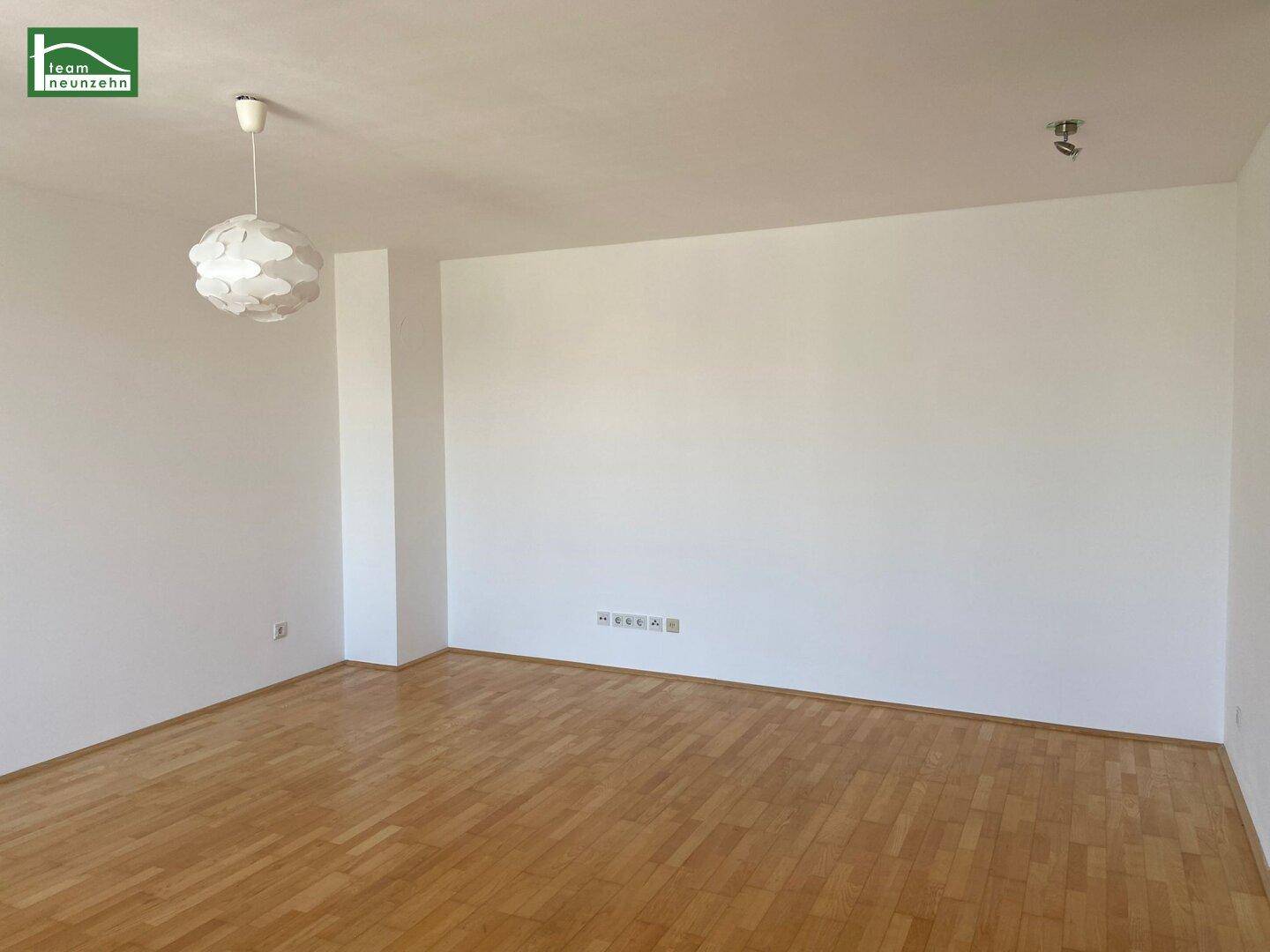Leerer Raum mit hellem Parkettboden und weißen Wänden, bereit zur individuellen Gestaltung.