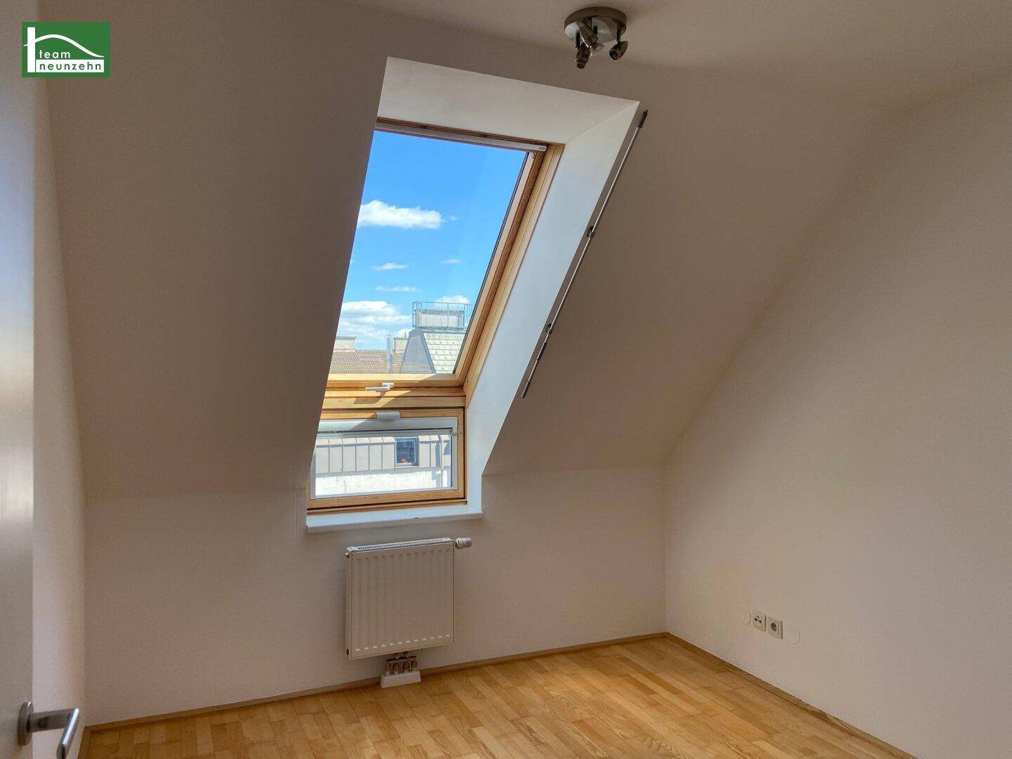 Gemütliches Zimmer im Dachgeschoss mit hellem Parkettboden und großem Dachfenster.