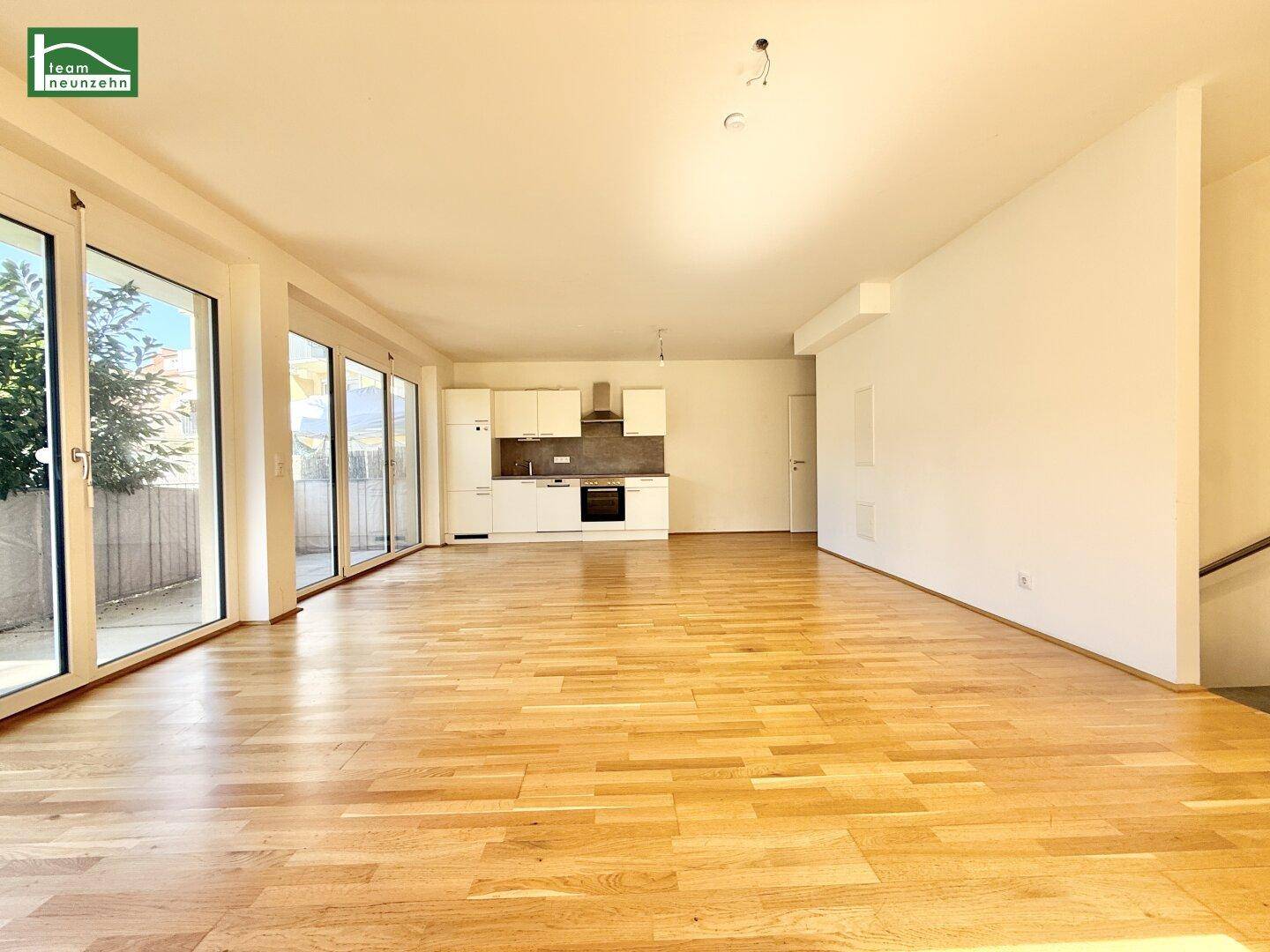 Geräumiger, offener Wohnbereich mit viel Tageslicht, Parkettboden und moderner Einbauküche.