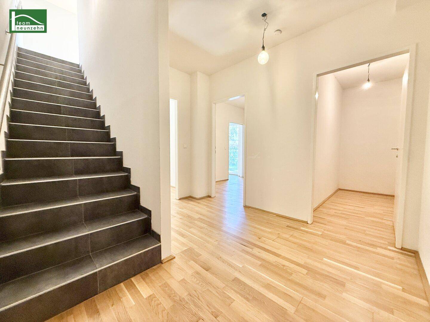 Geräumiger Flur mit Treppe und Parkettboden, der zu den oberen Etagen führt.