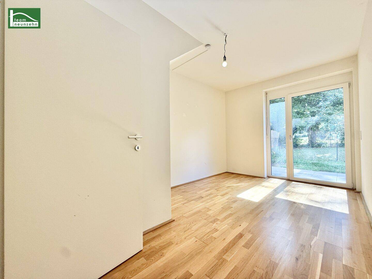 Helles Zimmer mit Holzboden und direktem Zugang zu einem grünen Außenbereich, ideal als Schlaf- oder Arbeitszimmer.