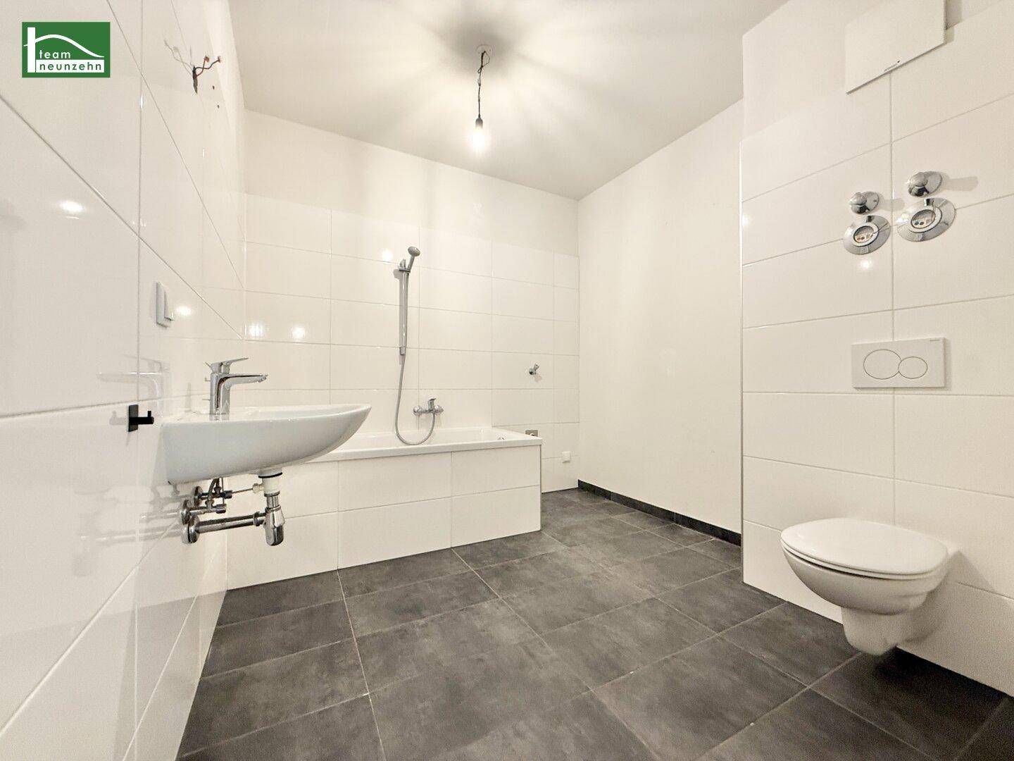 Modernes Badezimmer mit Badewanne, wandhängender Toilette, Waschbecken und weißen Fliesen.