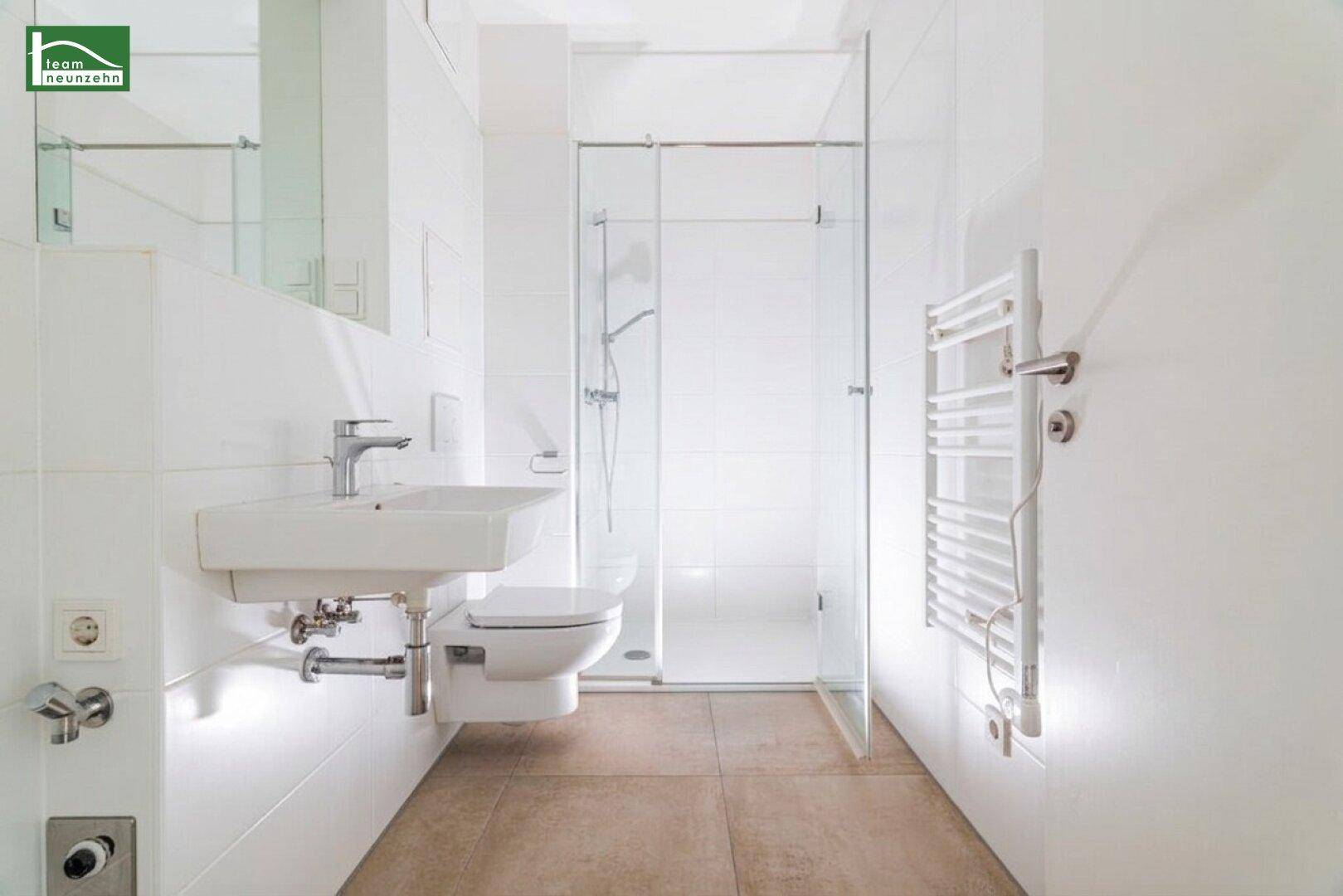 Modernes Badezimmer mit begehbarer Dusche, wandhängendem WC und beheiztem Handtuchhalter.