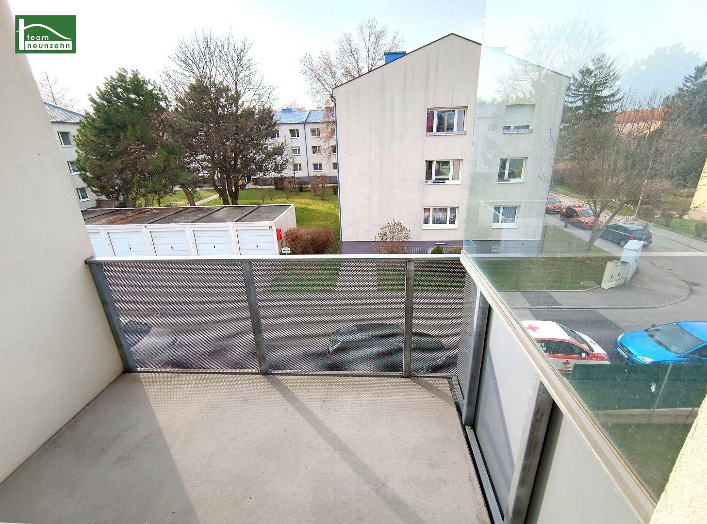 Balkon mit moderner Glas- und Metallbrüstung und Blick auf die umliegende Wohngegend.