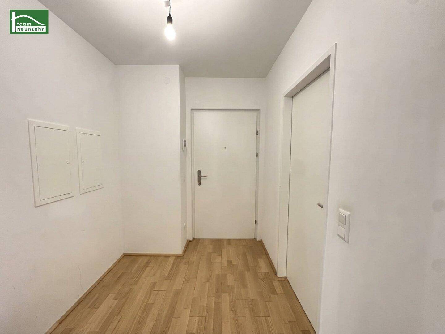Heller Eingangsbereich mit Parkettboden und weiß gestrichenen Wänden.