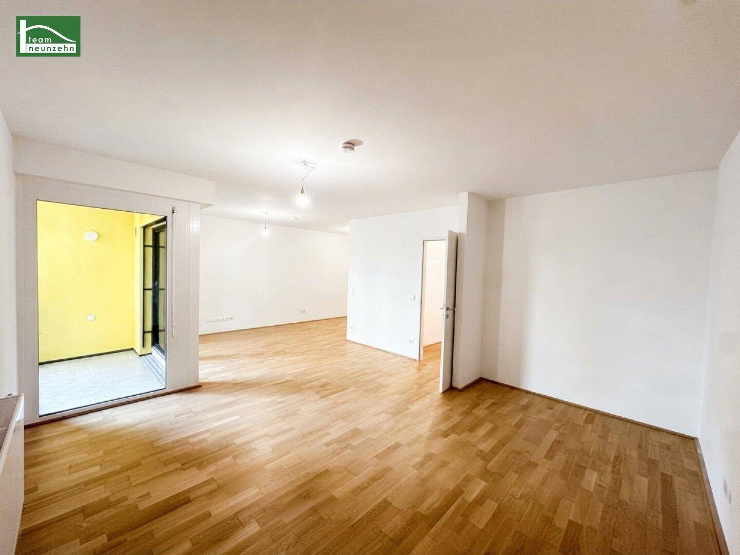 Lichtdurchfluteter Wohnbereich mit Parkettboden und großem Zugang zum Außenbereich.