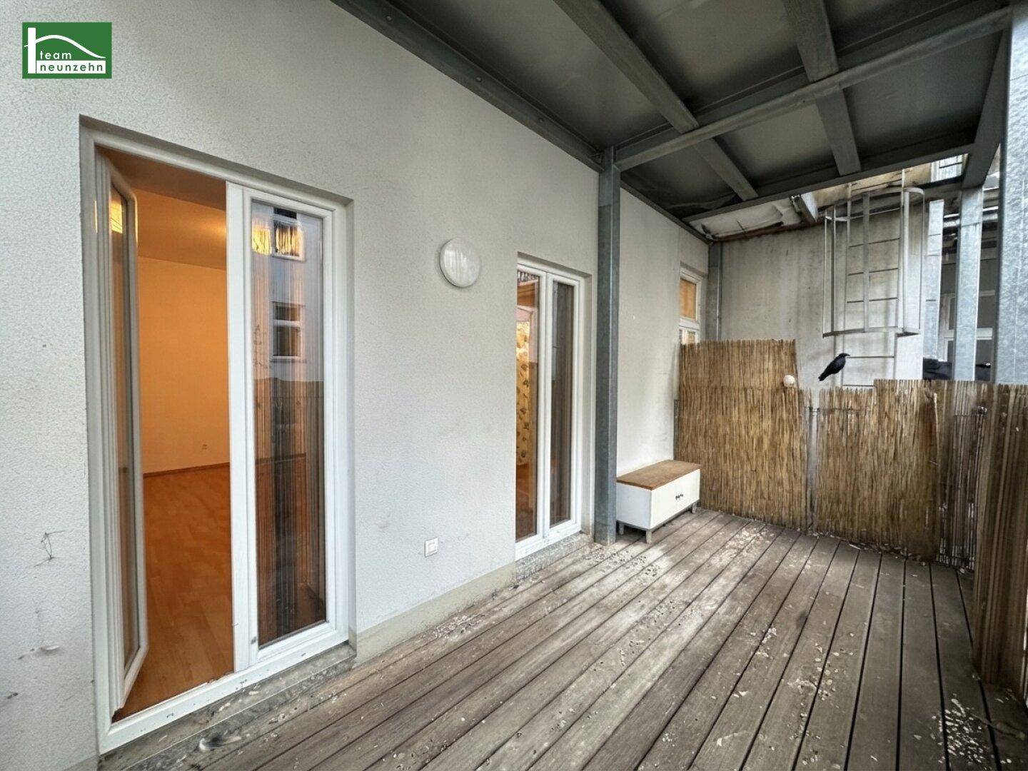 Kleiner Balkon mit Holzfußboden und Bambusverkleidung, zugänglich vom Innenbereich.