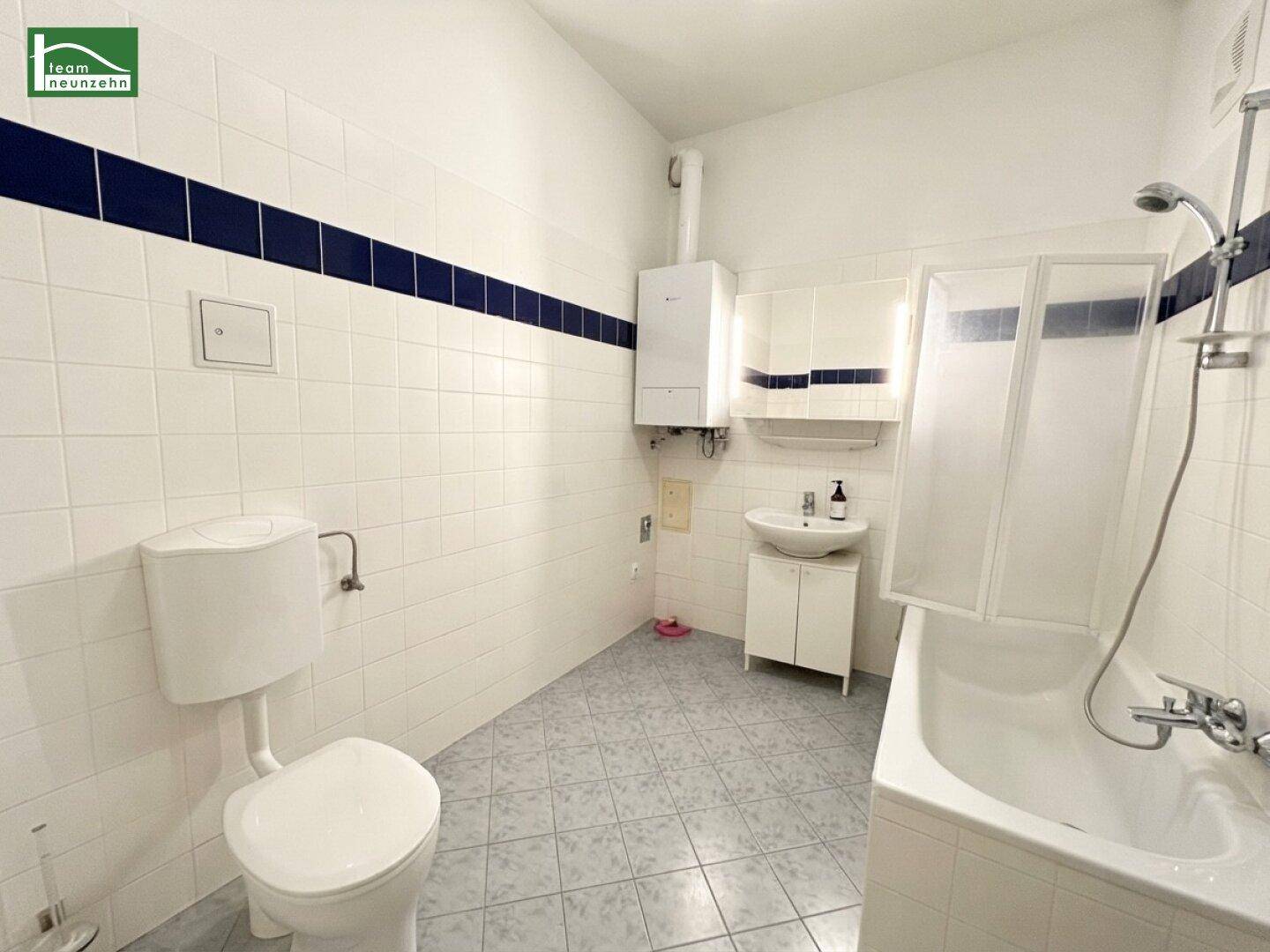 Gefliestes Badezimmer mit Badewanne, Dusche, WC und Waschbecken, in schlichtem Design.