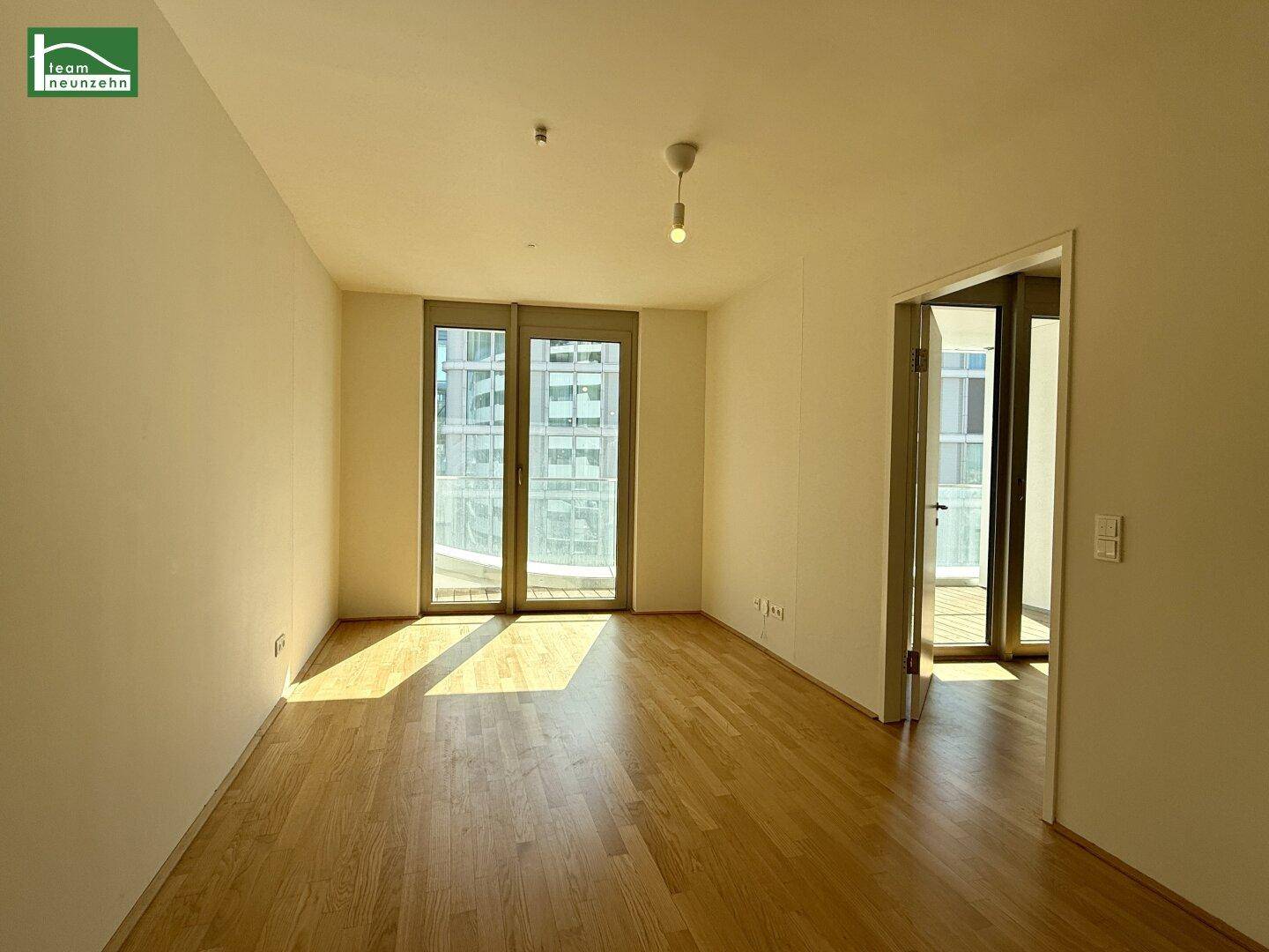 Lichtdurchfluteter Wohnraum mit großen Fenstern und Zugang zu einem Balkon, bietet viel Tageslicht.