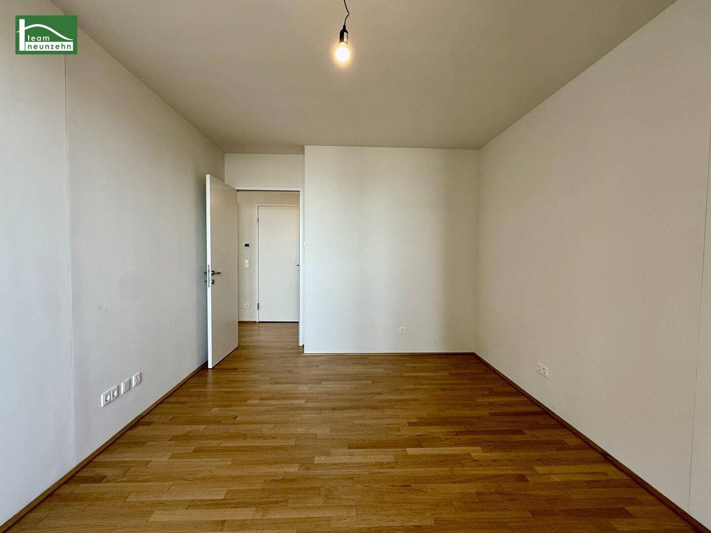 Helles Schlafzimmer mit Holzboden und weiß gestrichenen Wänden, bereit zur Einrichtung.