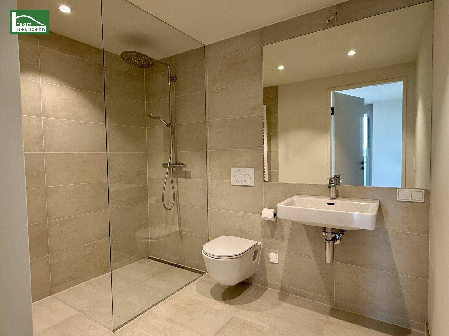 Modernes Badezimmer mit begehbarer Dusche, Wand-WC und großem Spiegel.