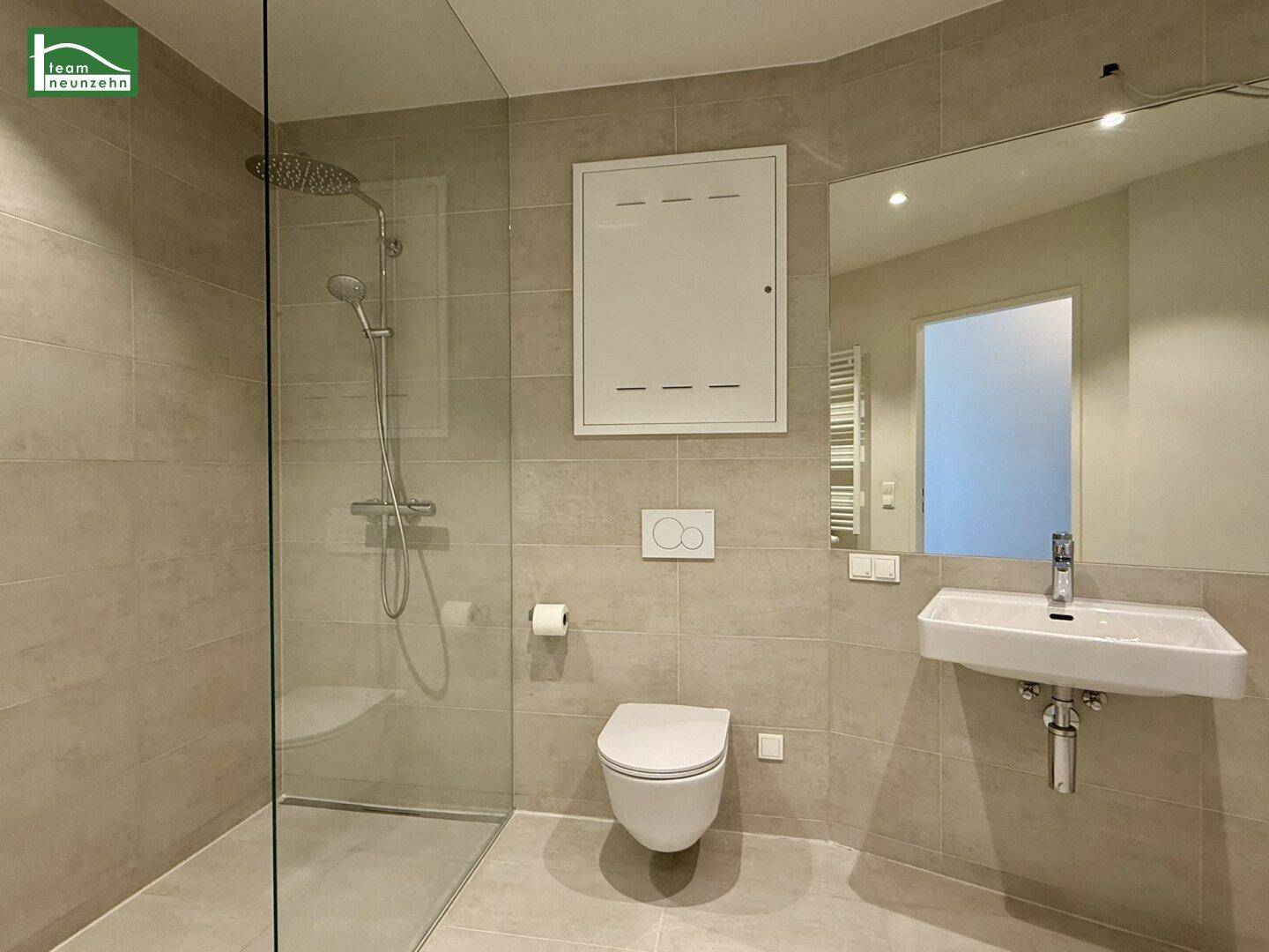 Modernes Badezimmer mit begehbarer Dusche, Wand-WC und hellen Fliesen.