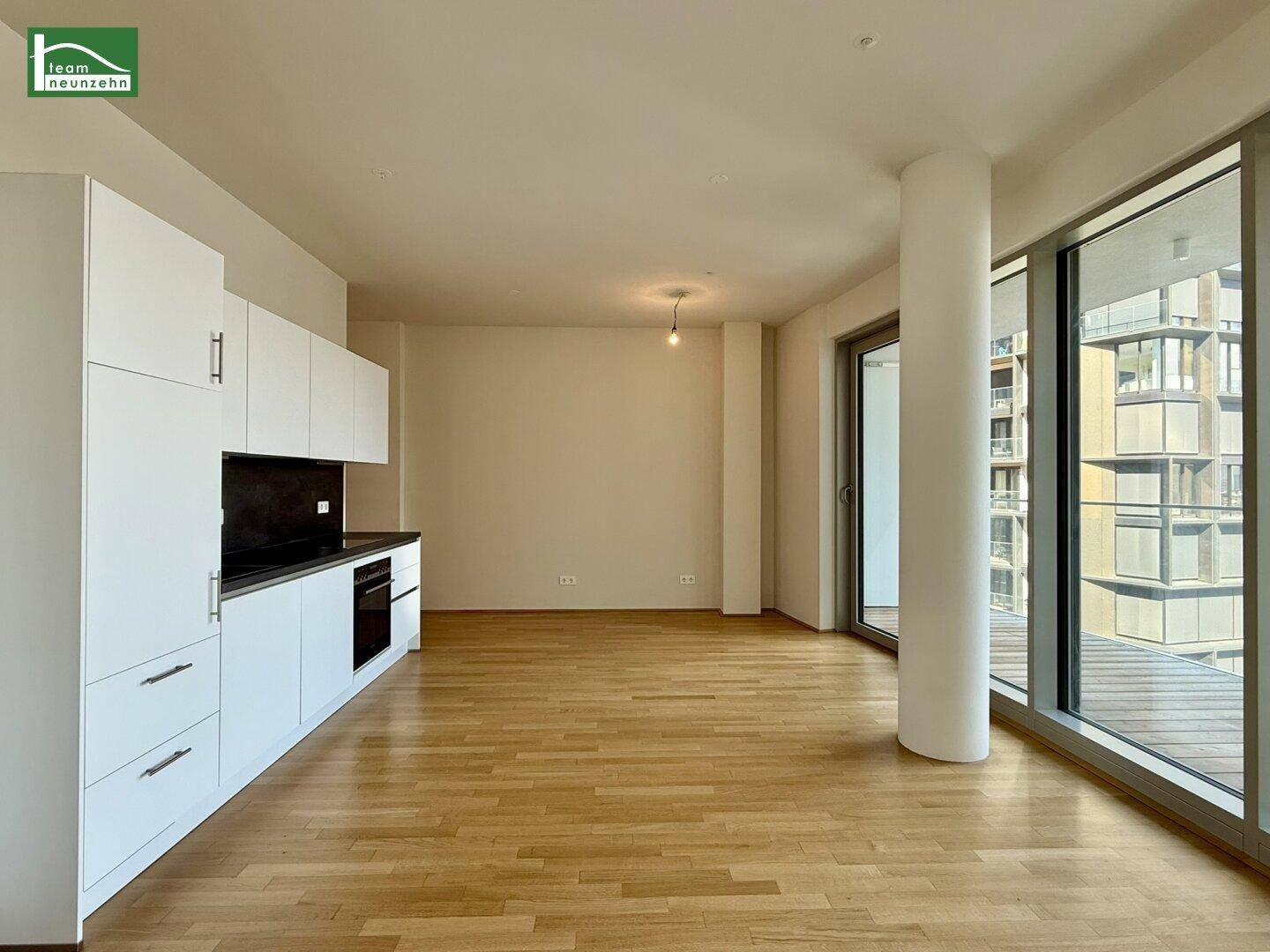Moderner Wohnbereich mit integrierter Küchenzeile, Holzboden und viel Tageslicht.