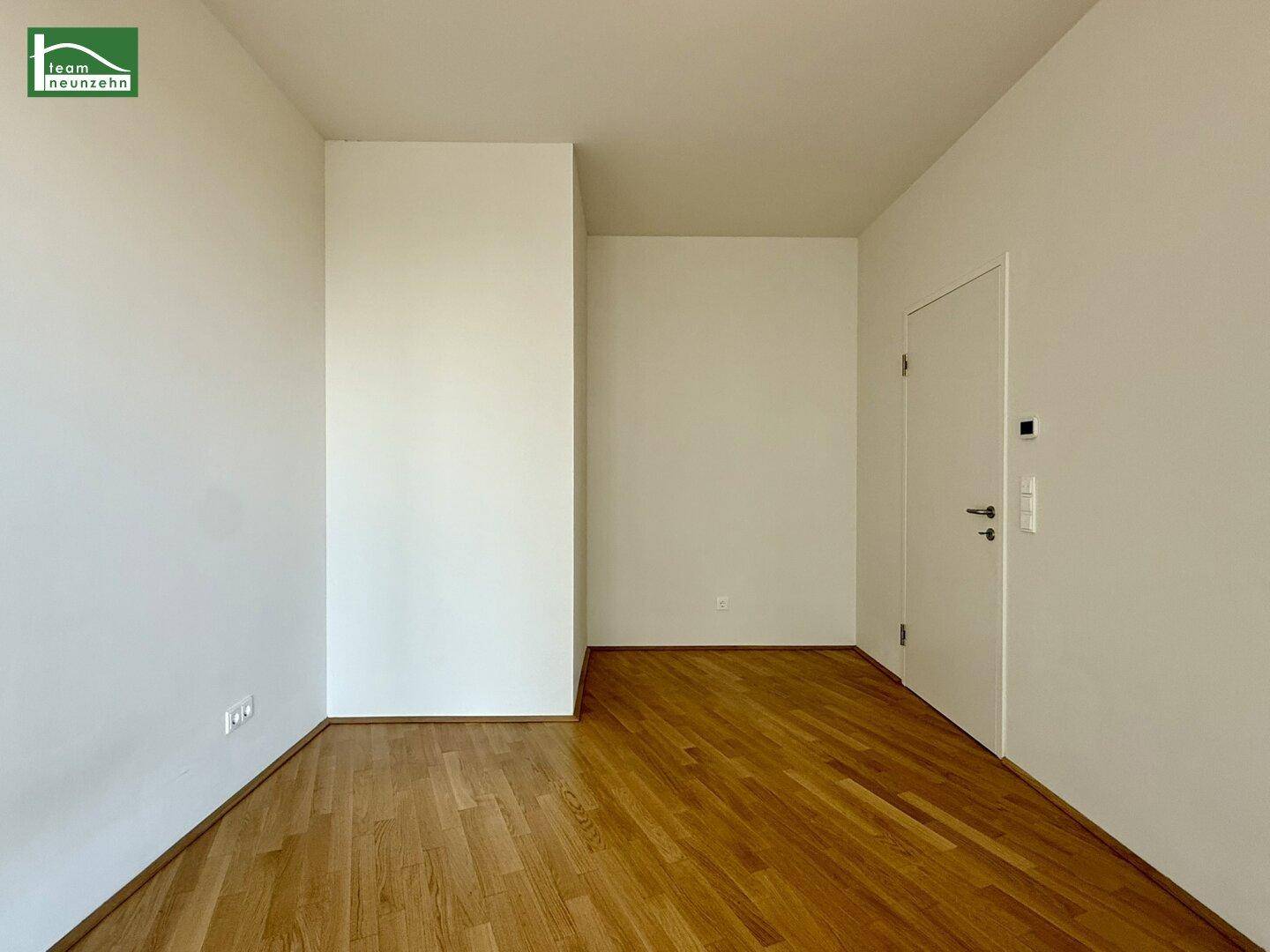Leeres Zimmer mit Parkettboden und weißer Tür, bereit zur individuellen Gestaltung.