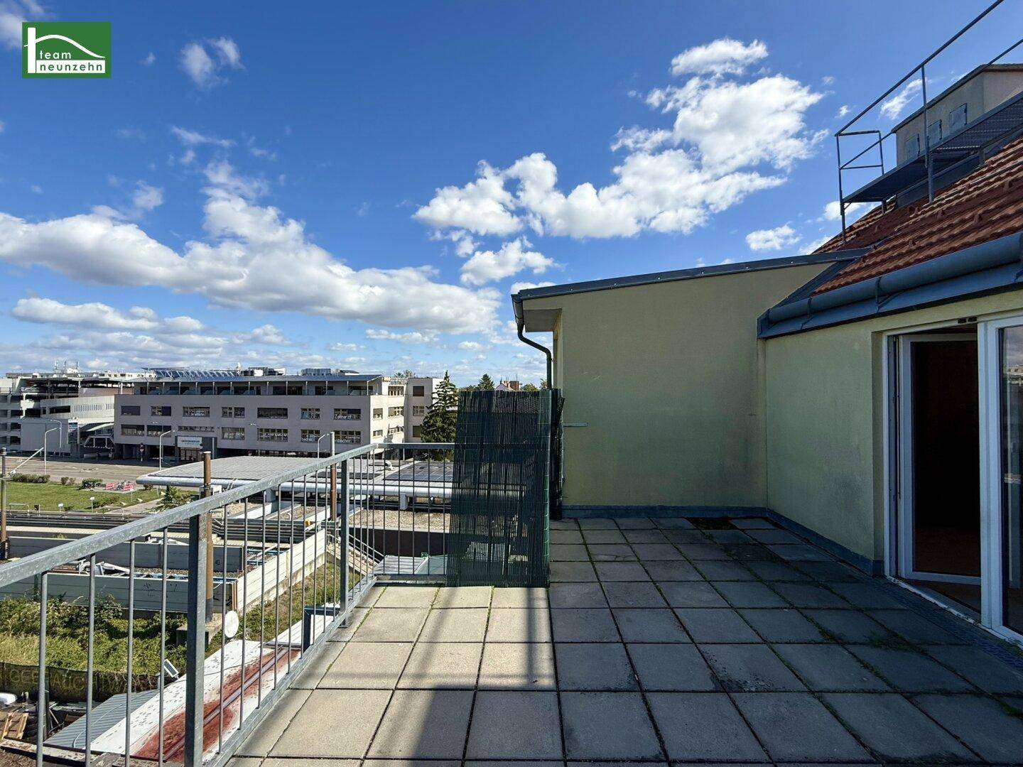 Große Dachterrasse mit Fliesenboden und Blick auf die umliegende Bebauung.