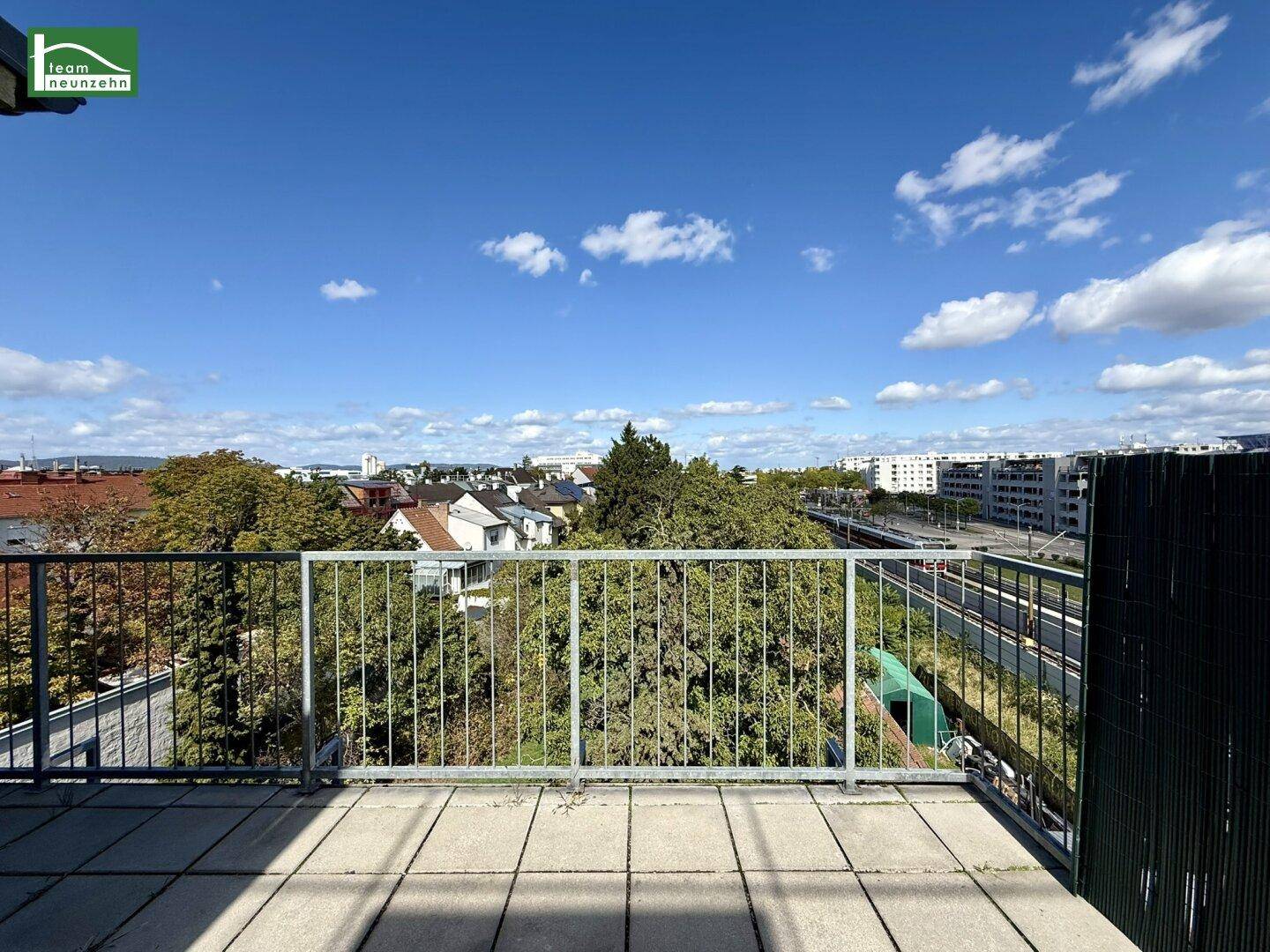 Weitläufige Dachterrasse mit Panoramablick über die Stadt und viel Grün.