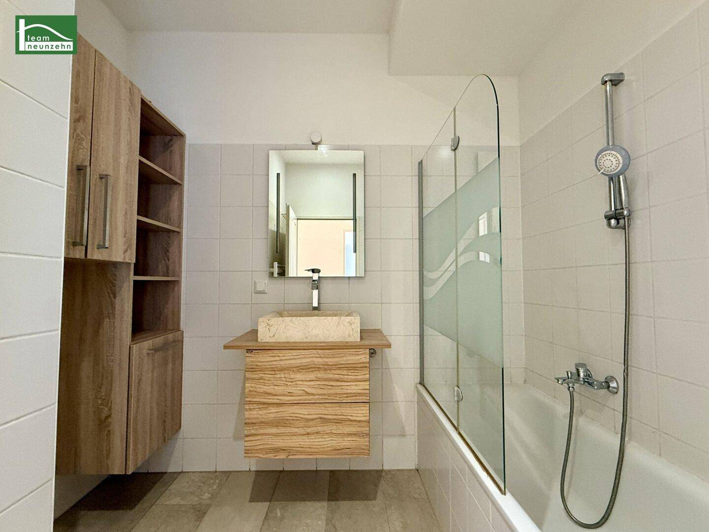 Modernes Badezimmer mit Badewanne, Duschwand und Holzwaschtisch mit Aufsatzbecken.