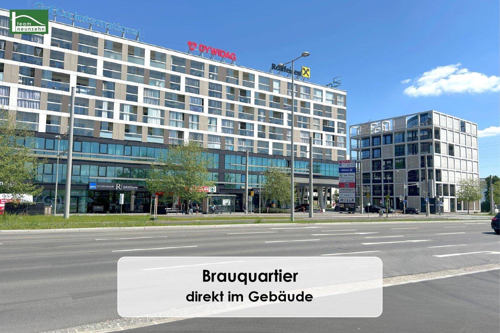 Großer moderner Gebäudekomplex mit Geschäften und Büros entlang einer belebten Straße.