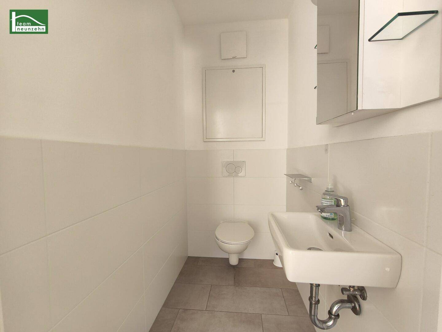 Separates WC mit Toilette, Waschbecken und Spiegelschrank.