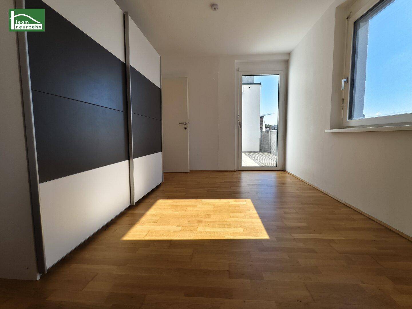 Schlafzimmer mit Holzboden, großem Schrank und Zugang zum Außenbereich.