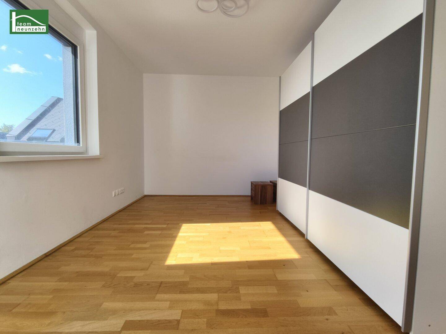 Geräumiges Schlafzimmer mit hellem Holzboden und großem Kleiderschrank.