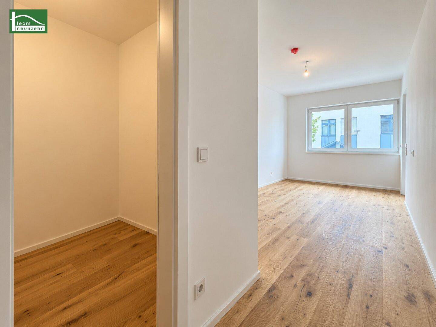 Helles Schlafzimmer mit Parkettboden und Zugang zu einem begehbaren Kleiderschrank.
