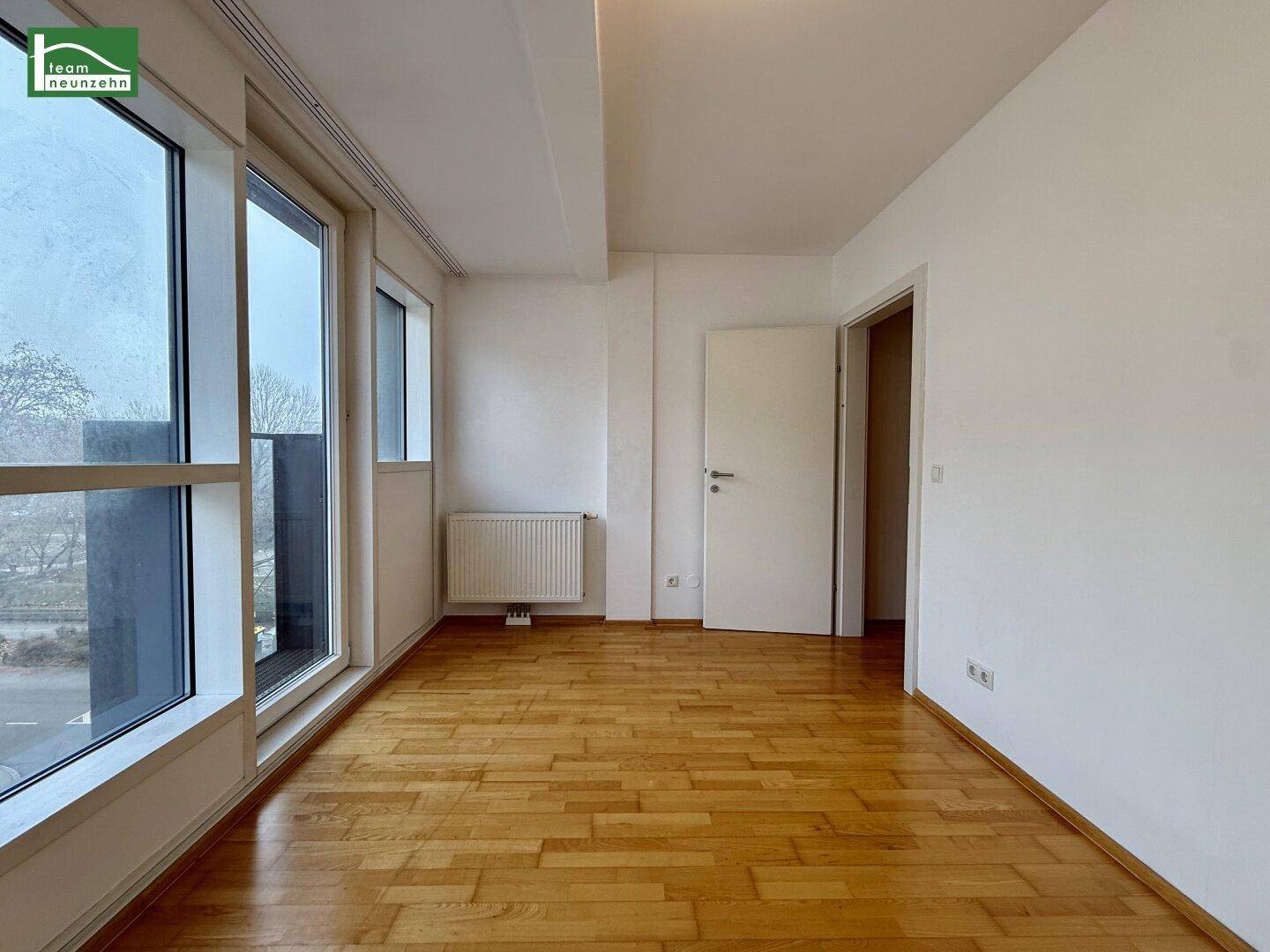 Helles Zimmer mit Parkettboden und großen Fenstern, ideal als Schlafzimmer oder Arbeitszimmer.
